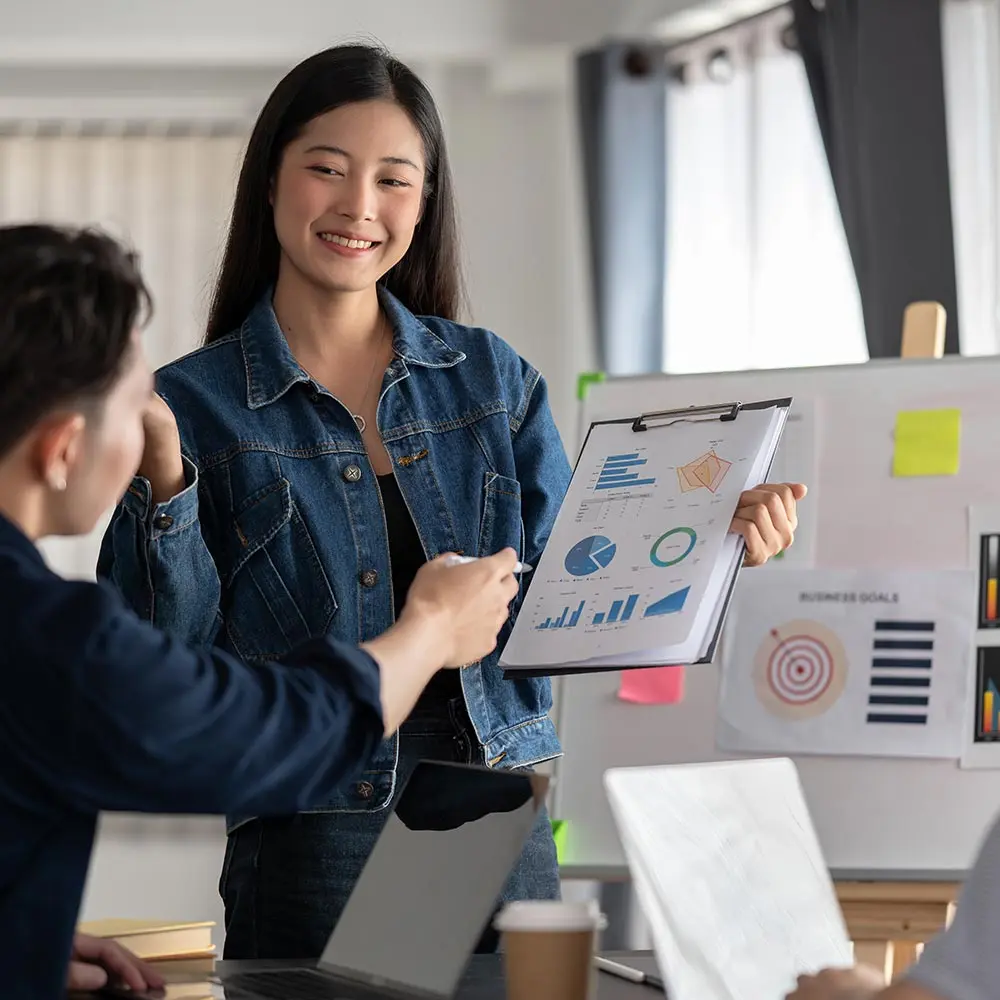 Two colleagues presenting marketing ideas on a whiteboard